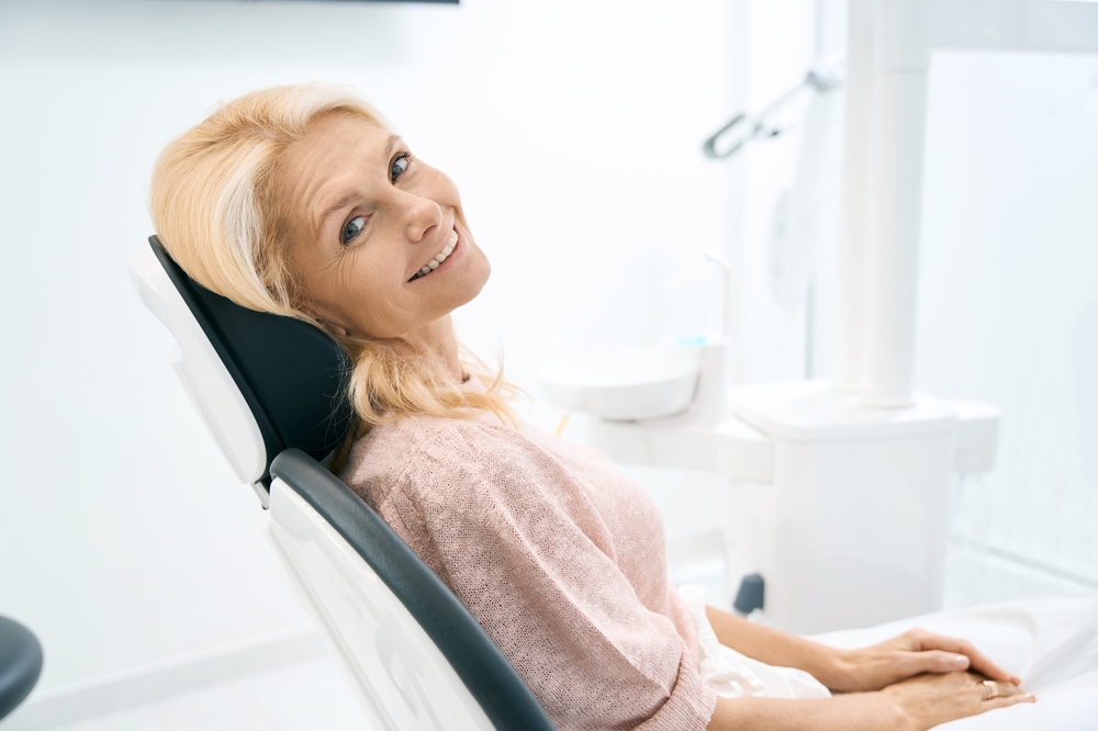 Smiling mature woman in dental chair – Root Canal Therapy in Long Beach CA A cheerful older woman smiles while sitting comfortably in a dental chair, reflecting trust and relief after expert care – Root Canal Therapy in Long Beach CA.
